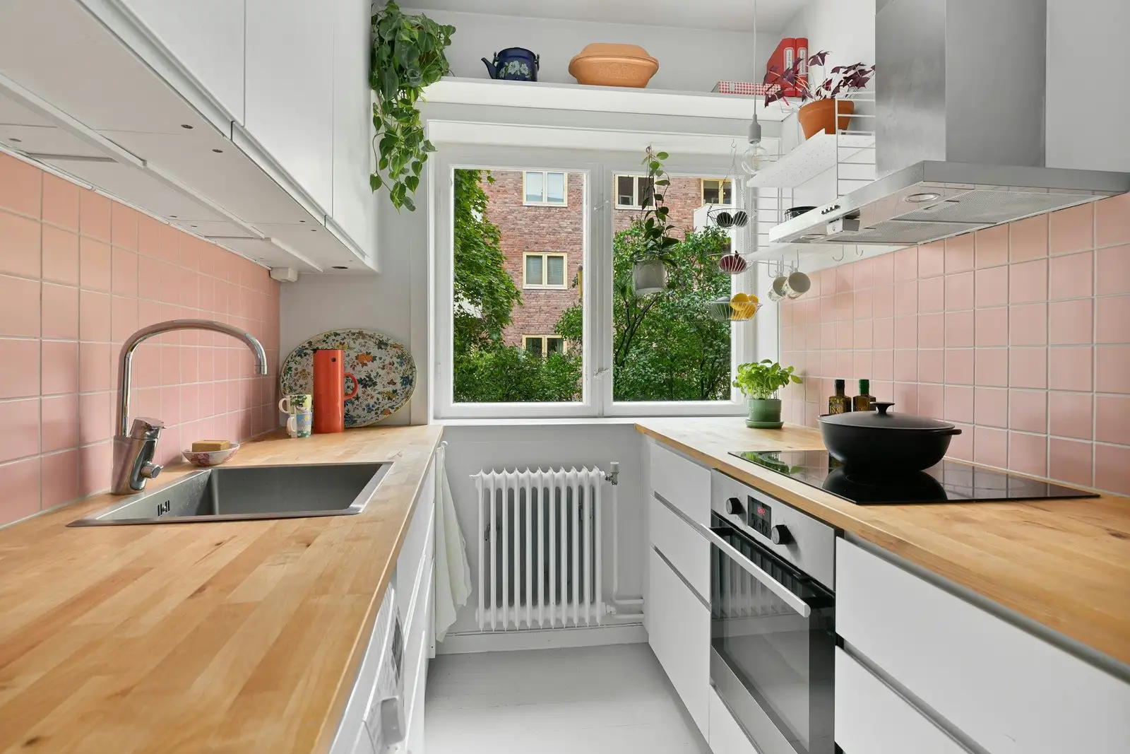 Galley kitchen with pink tiles and a window