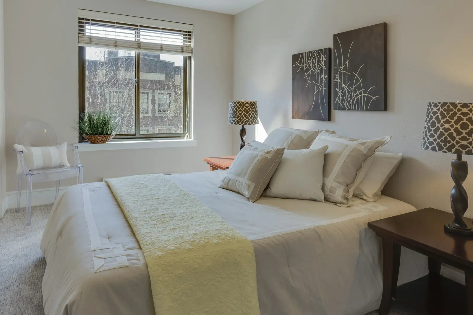 Bedroom with cream bedding and a window with blinds
