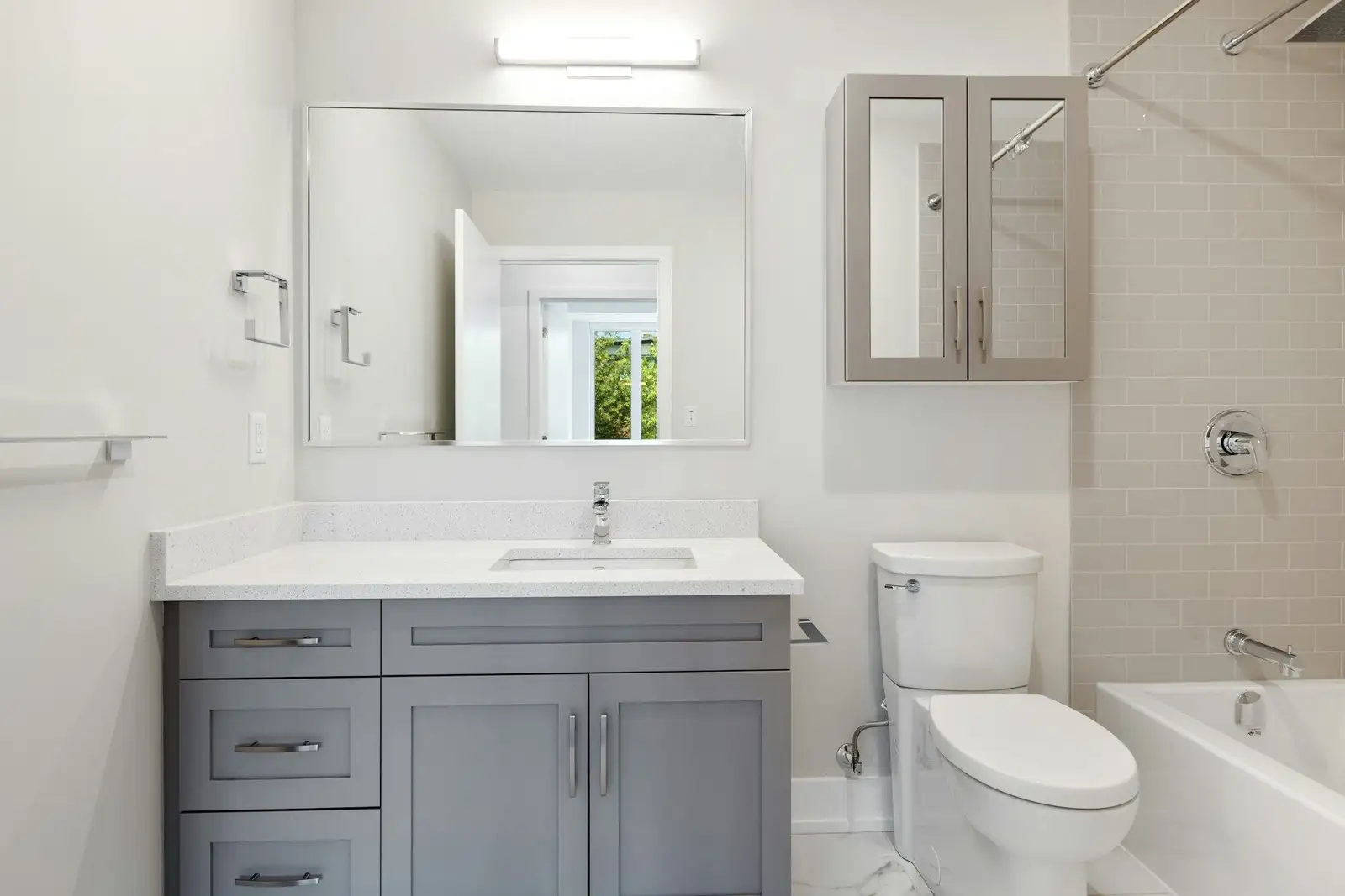 Bathroom with a grey vanity, a mirror cabinet and a tub