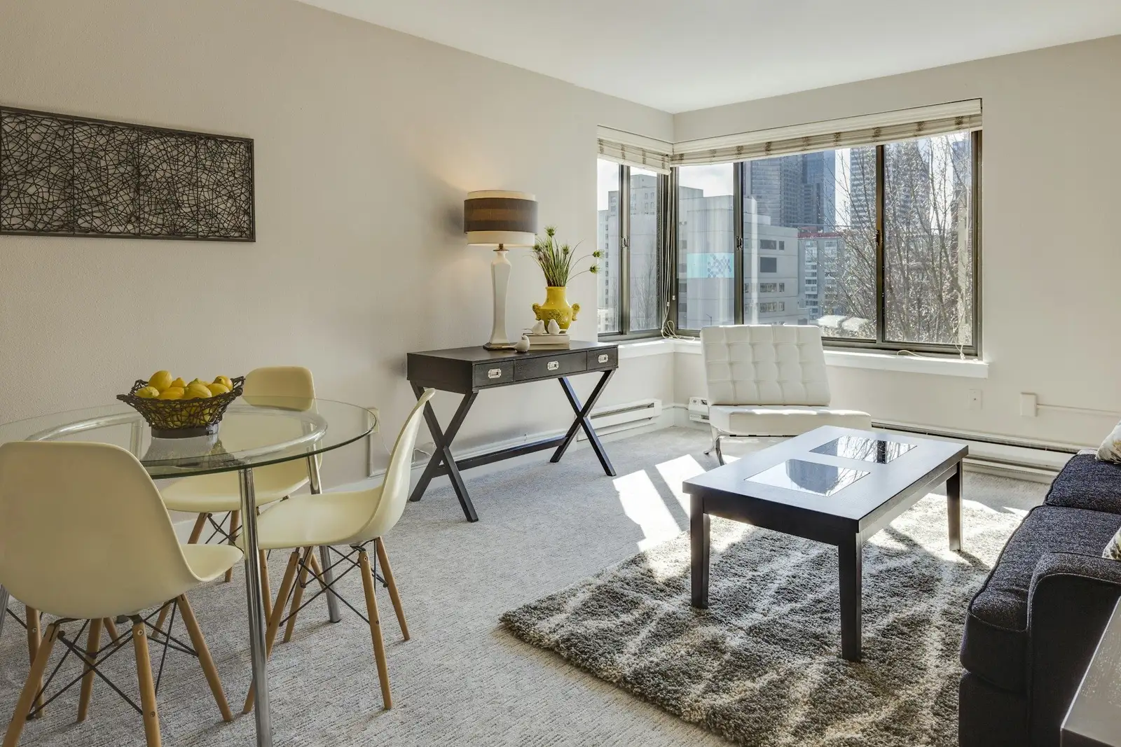 Living and dining room with a round glass table and corner windows