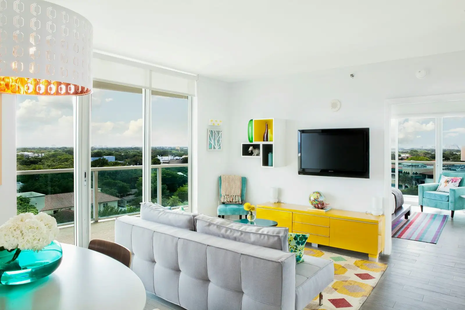 Living room with a grey sofa, a yellow sideboard and balcony doors