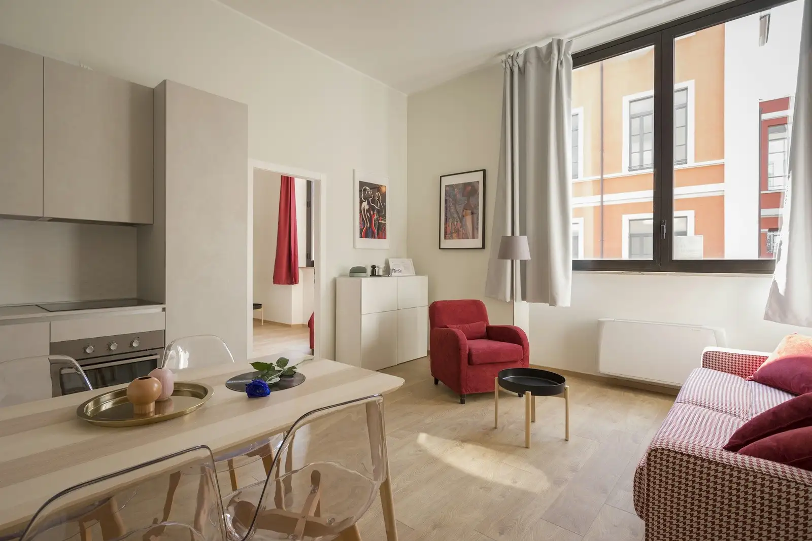 Open-plan living room with a red armchair and a compact kitchen
