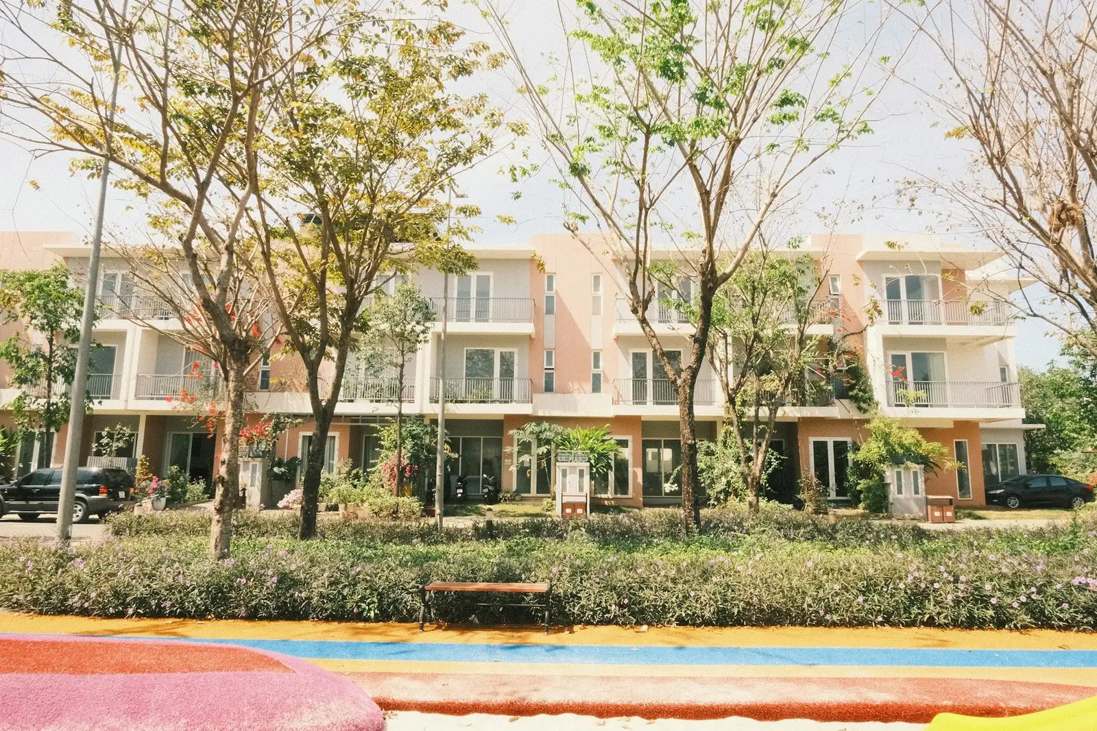 Three-storey townhouse row behind young trees