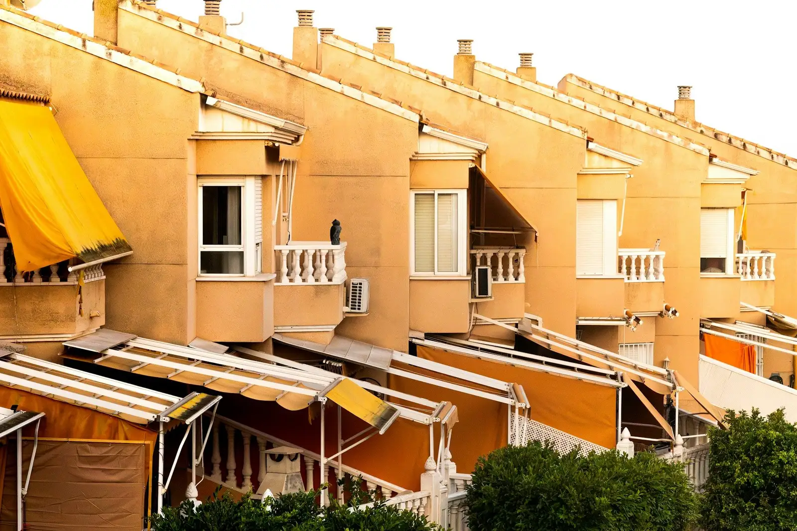 Row of ochre townhouses with awnings and small balconies