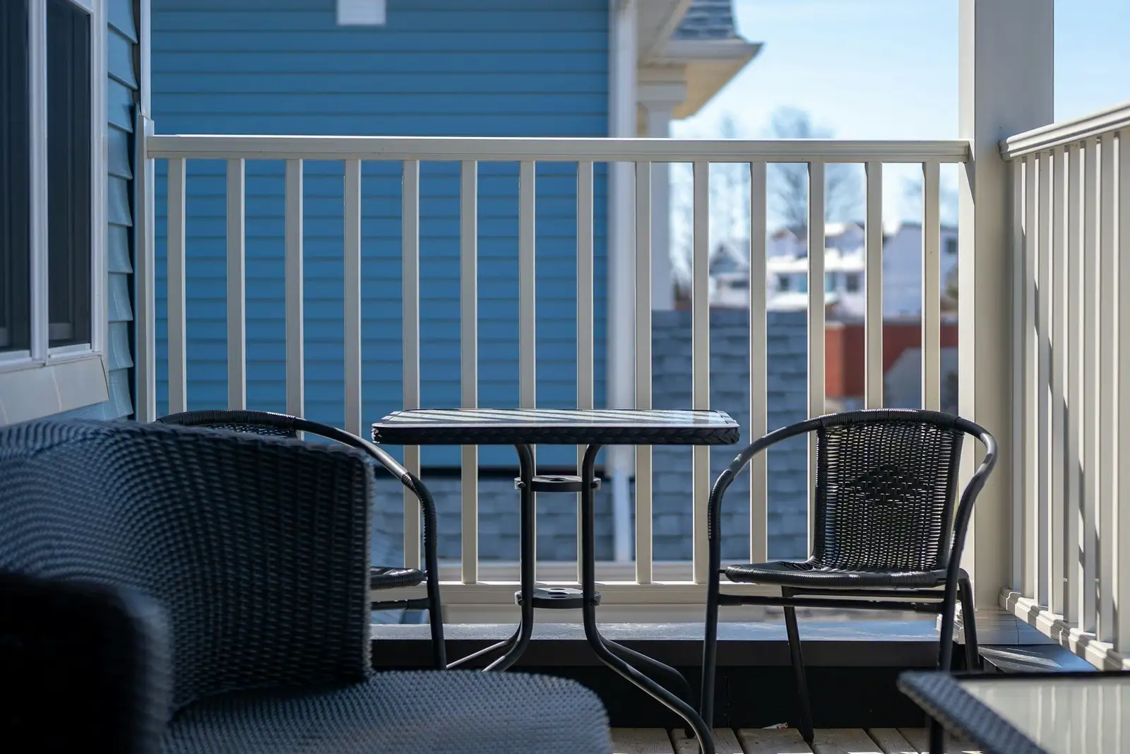 Balcony with a table and chairs behind white railings