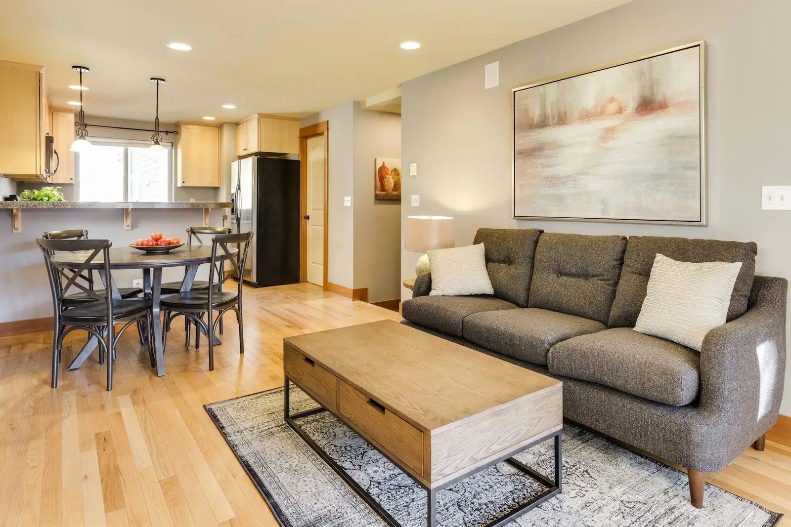Living room with a grey sofa and a dining area by the kitchen