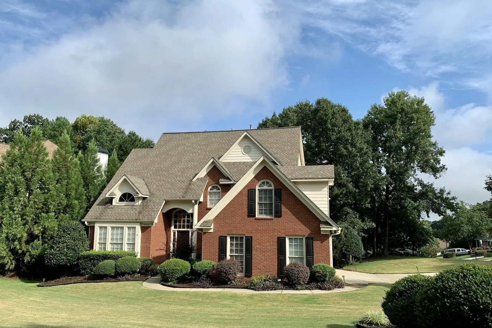 Brick two-storey house with a lawn and shrubs