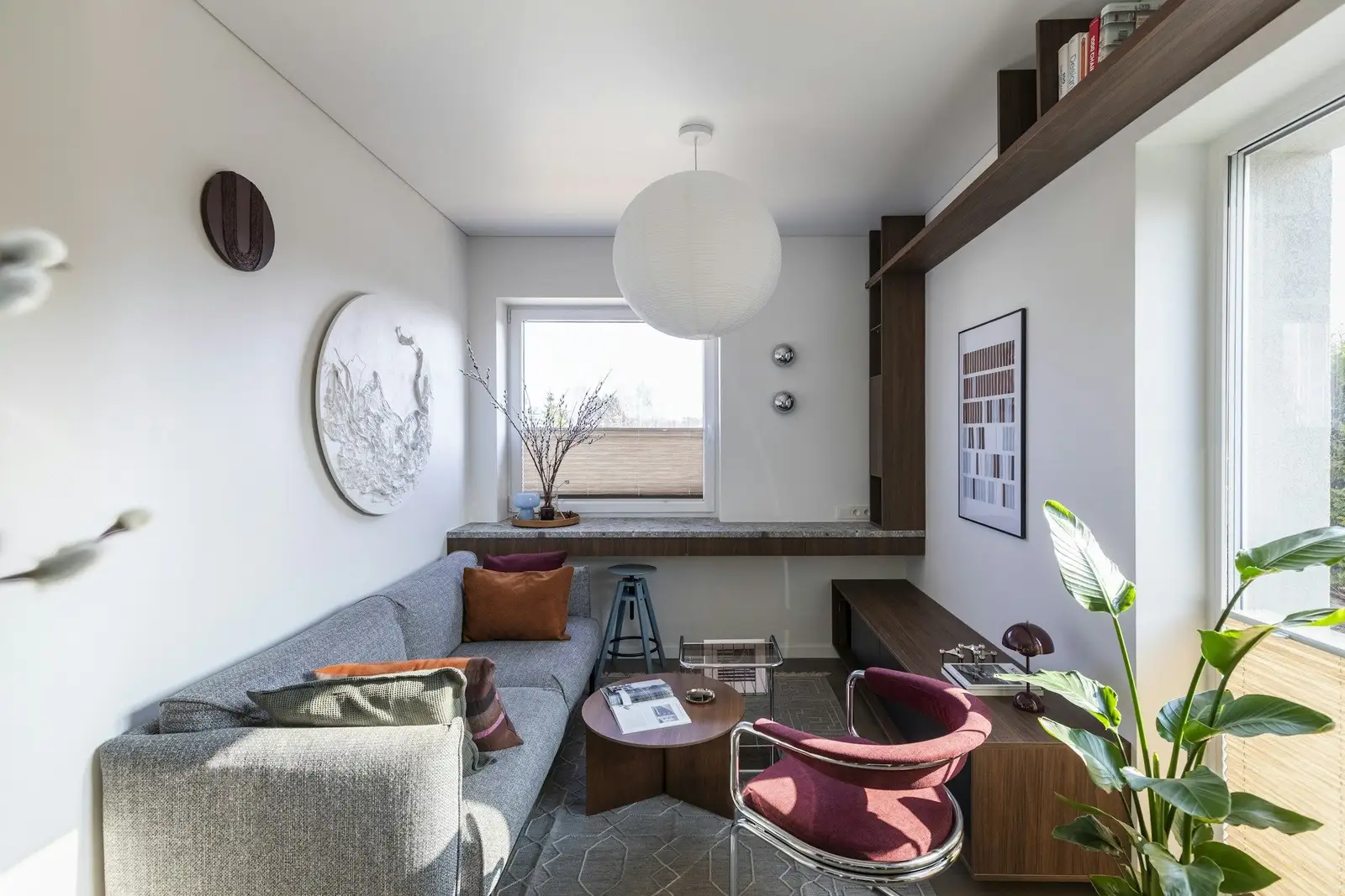 Narrow living room with a grey sofa and a window desk