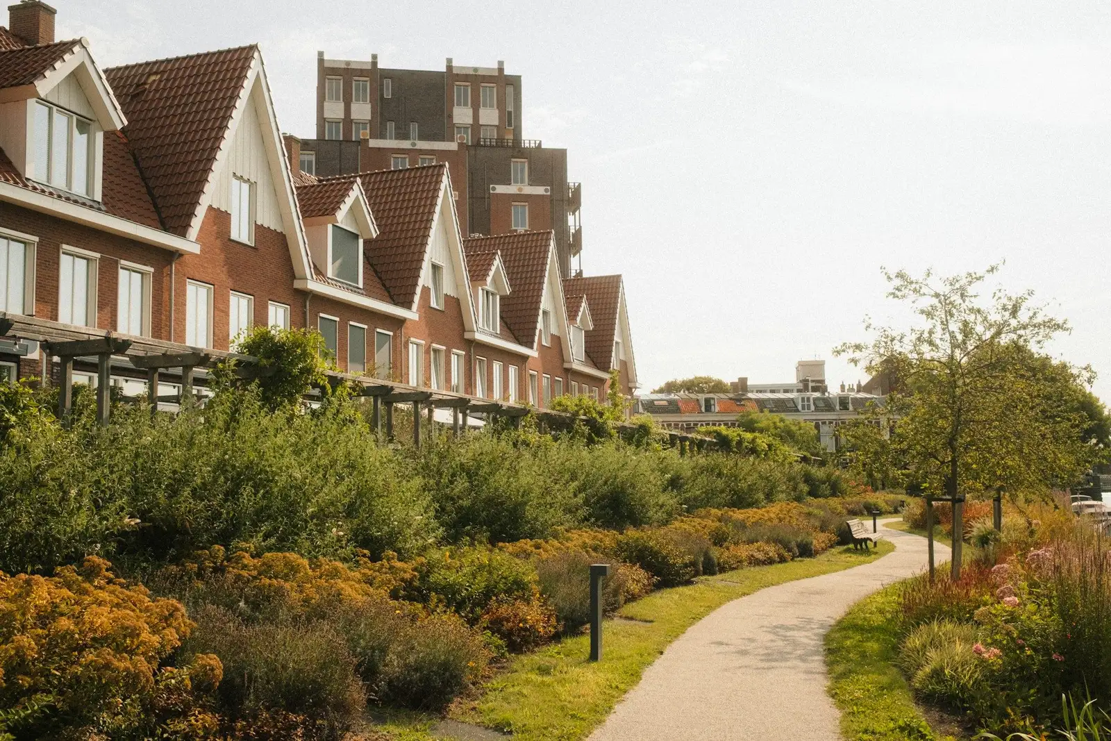 Row of brick townhouses with steep gables beside a garden path